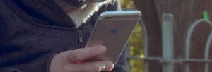 uma mulher olhando para um iphone que a arouca consertou a tela, Conserto Assistência iPhone